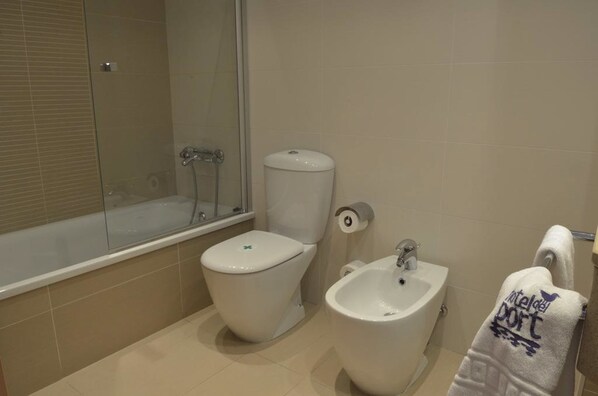 A bathroom with a toilet, bidet, and bathtub.