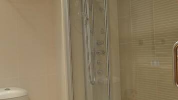 Un baño moderno con ducha de vidrio, inodoro y perchero para toallas.