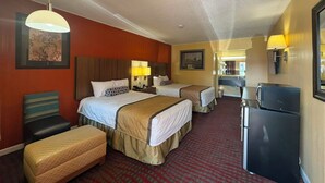 A hotel room with two beds, a desk, a refrigerator, and a chair.