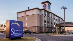 A Sleep Inn & Suites building with a signboard, parking area, and a covered walkway. - Sleep Inn & Suites Elk City Route 66 (Elk City)