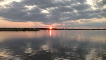 A calm lake at sunset with a clear sky and distant horizon.