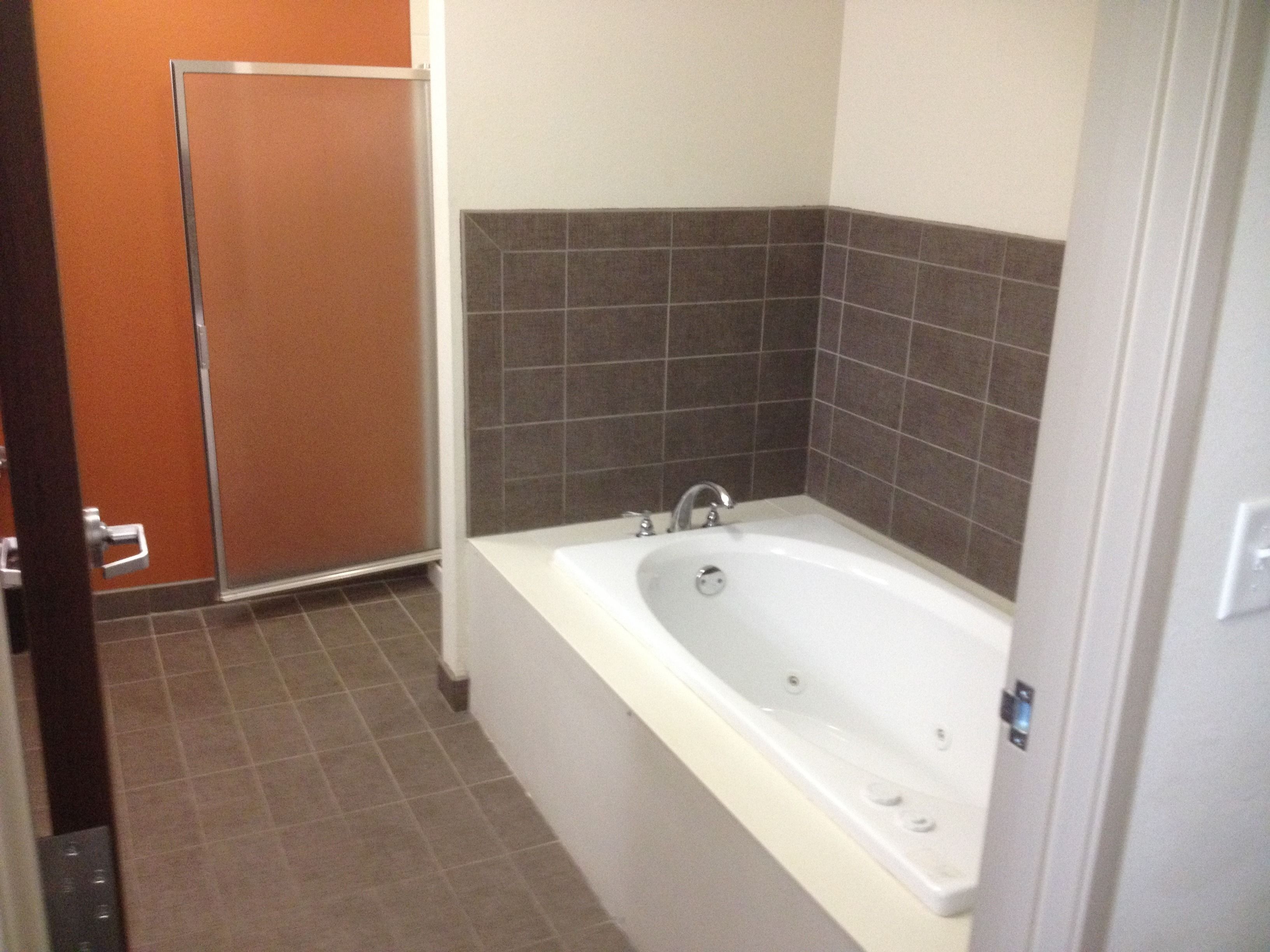 Un baño con bañera, ducha y paredes de azulejos.