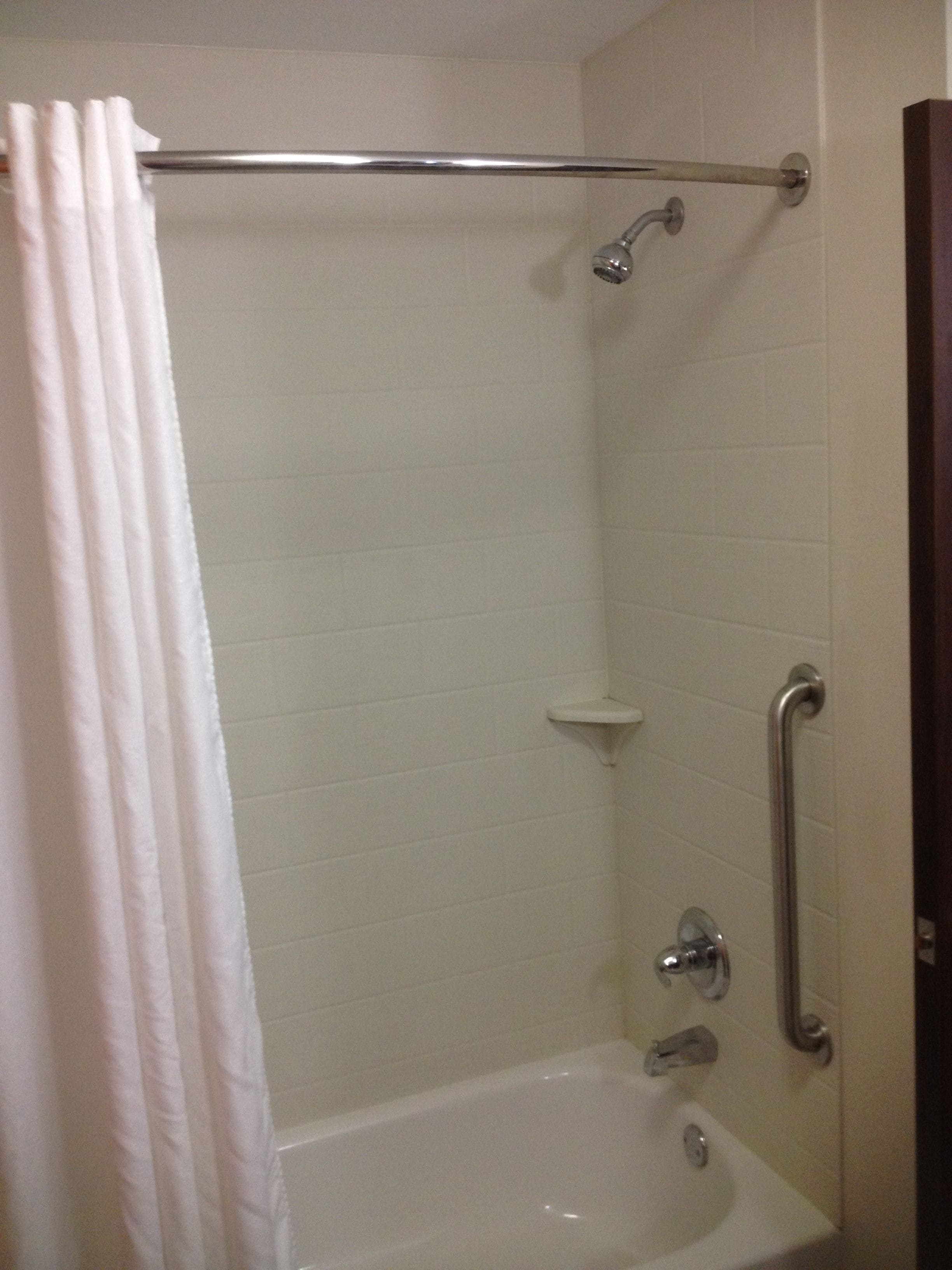 Une salle de bain équipée d’une baignoire, d’une douche et d’une barre d’appui.
