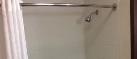 Une salle de bain équipée d’une baignoire, d’une douche et d’une barre d’appui.