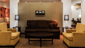 A lobby with a brown sofa, two yellow armchairs, a coffee table, and a wall-mounted picture frame. - Sleep Inn & Suites Elk City Route 66 (Elk City)