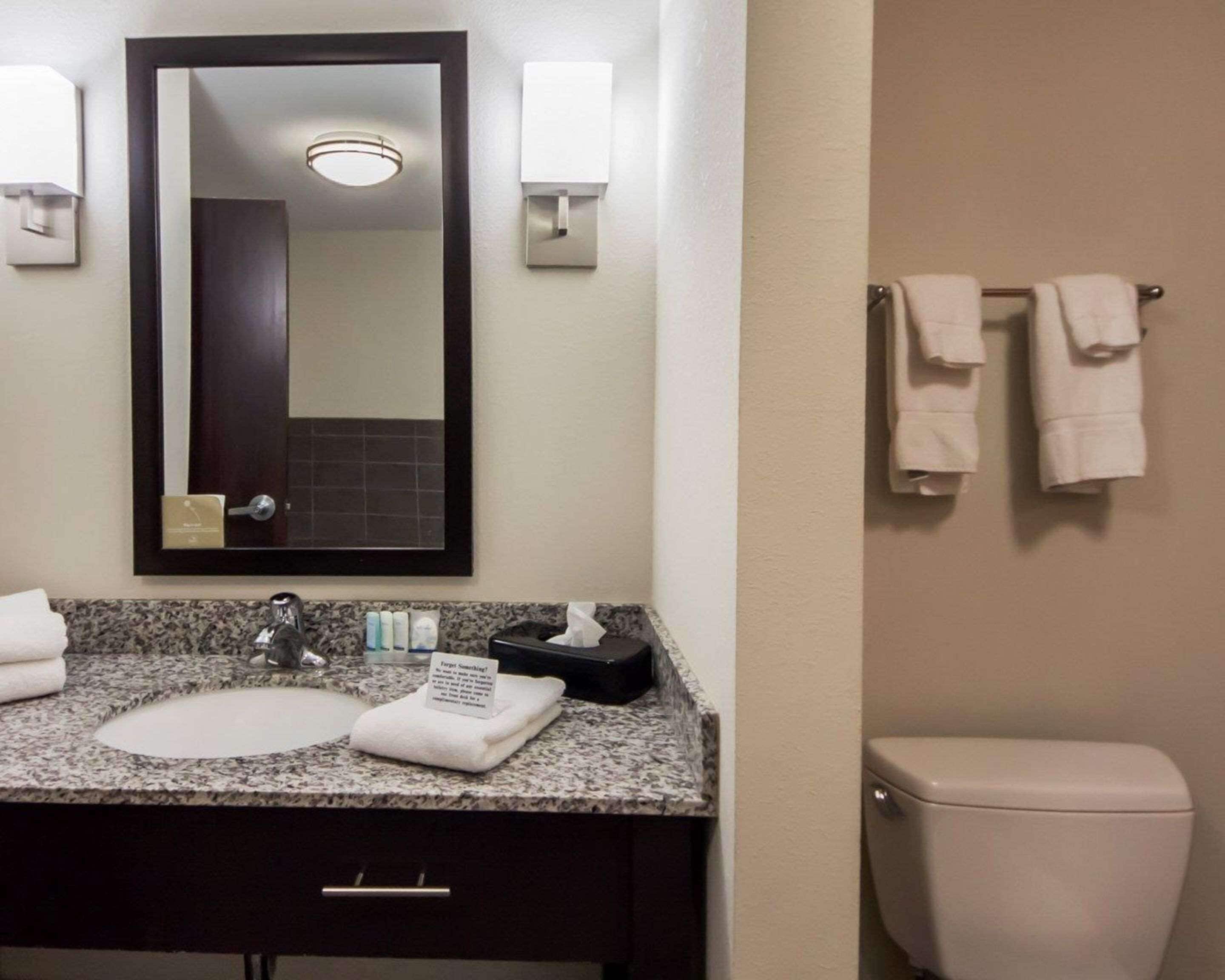 A bathroom with a sink, mirror, towel rack, and toilet.