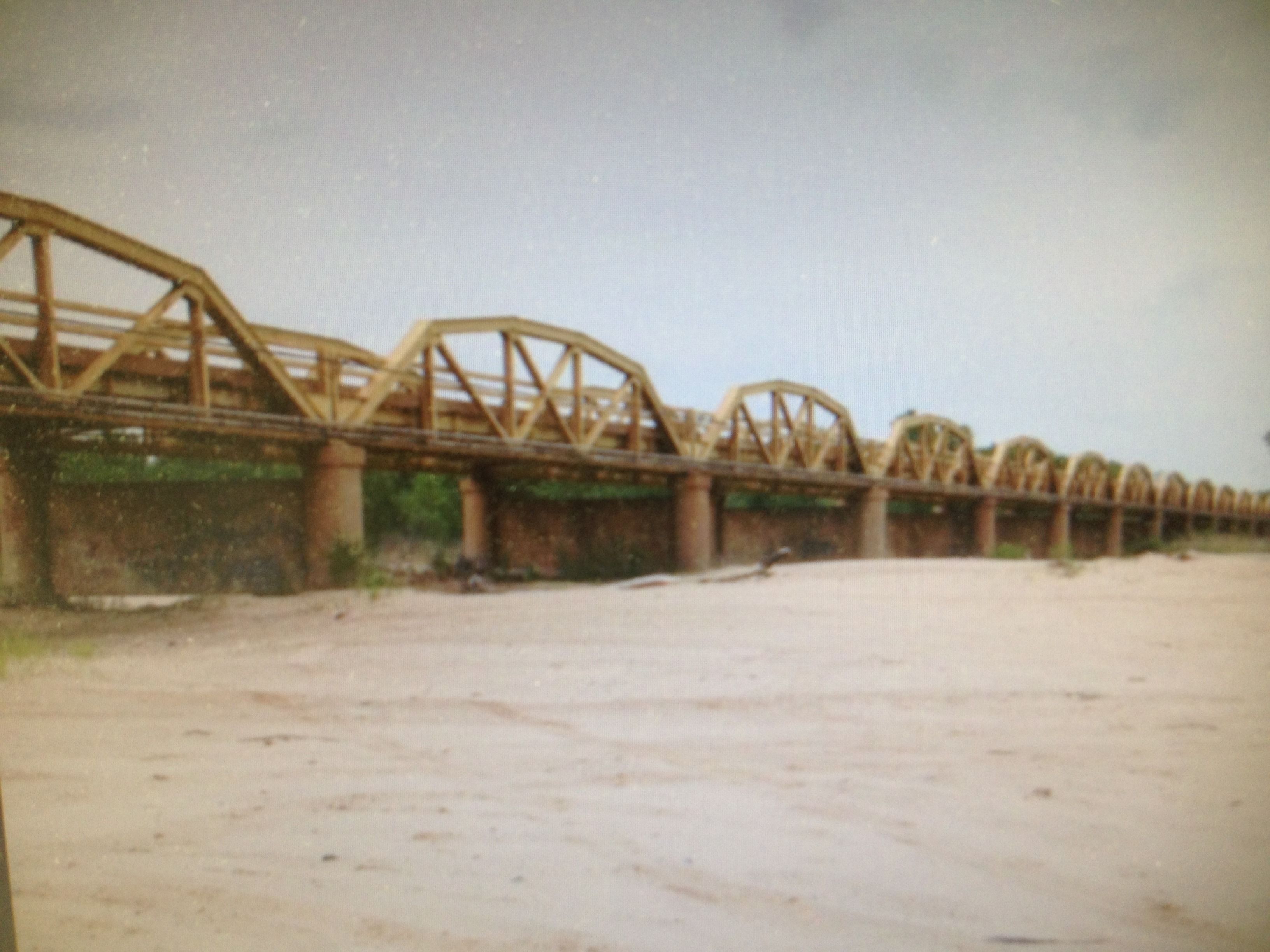 A large, empty bridge with multiple arches and a sandy ground.