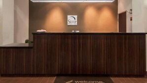 A reception desk with a sign reading "Sleep Inn & Suites" and a welcome mat with "Welcome Elk City" text. - Sleep Inn & Suites Elk City Route 66 (Elk City)