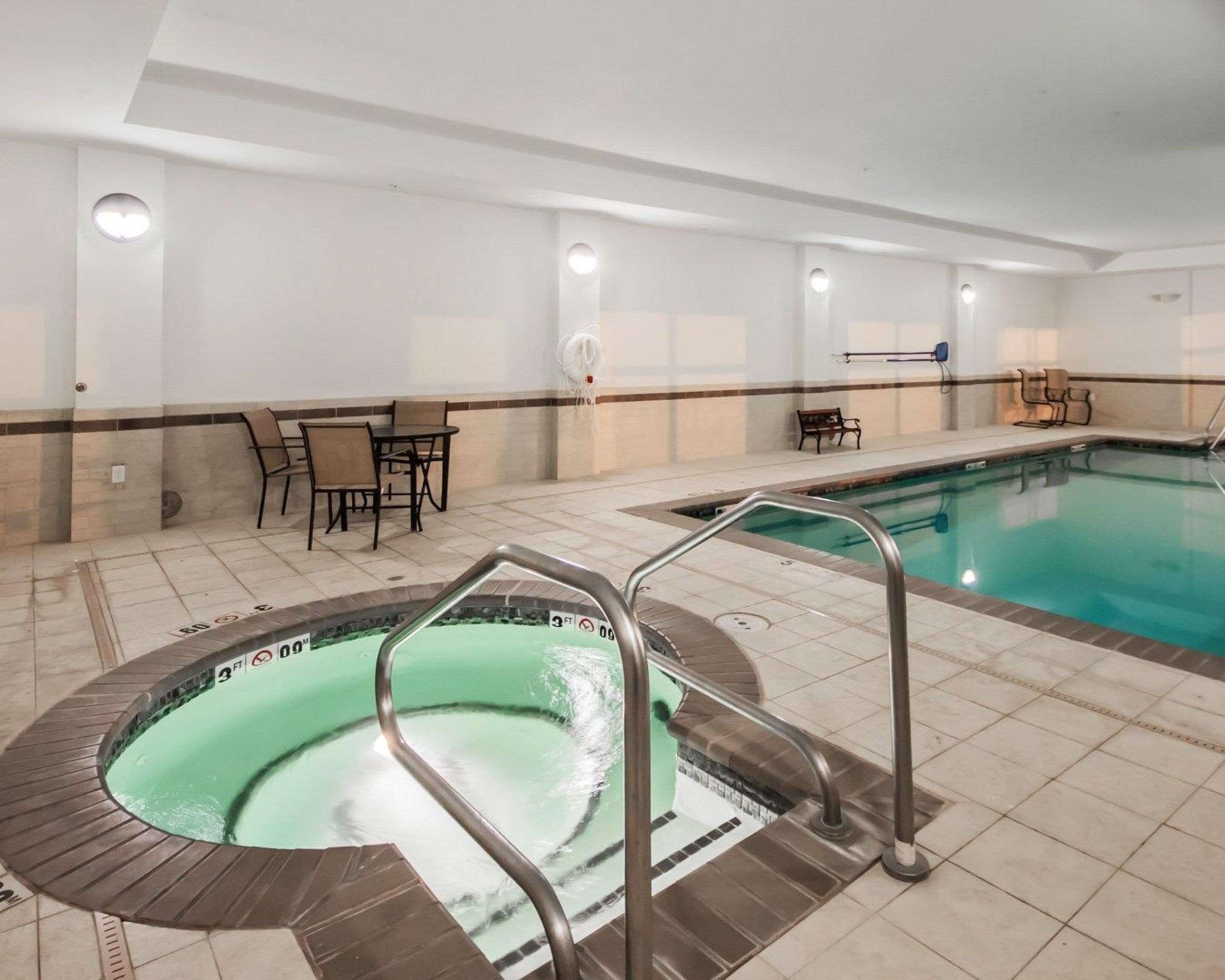 Ein Innenpool mit Whirlpool, Fliesenböden und Sitzbereichen.