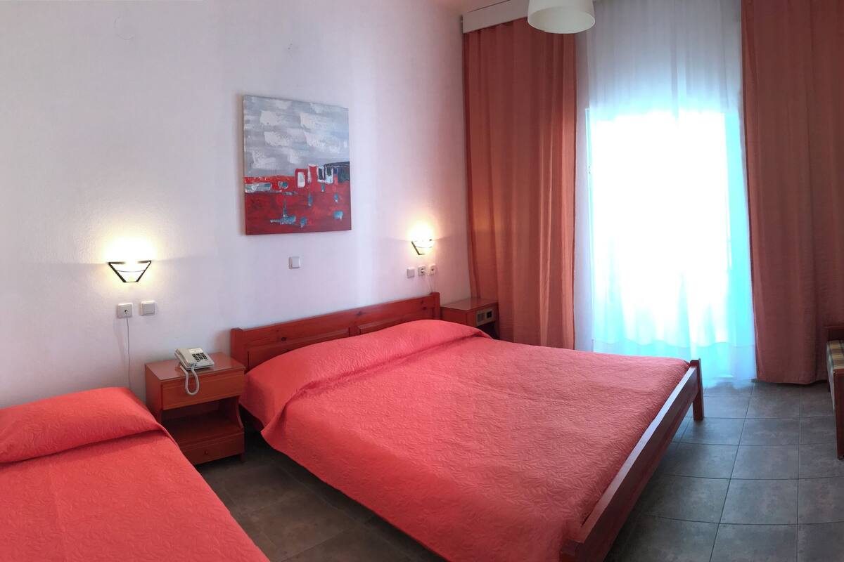 Ein Hotelzimmer mit zwei Betten, einem Schreibtisch mit Stuhl, einem Fernseher und einem Bild an der Wand.