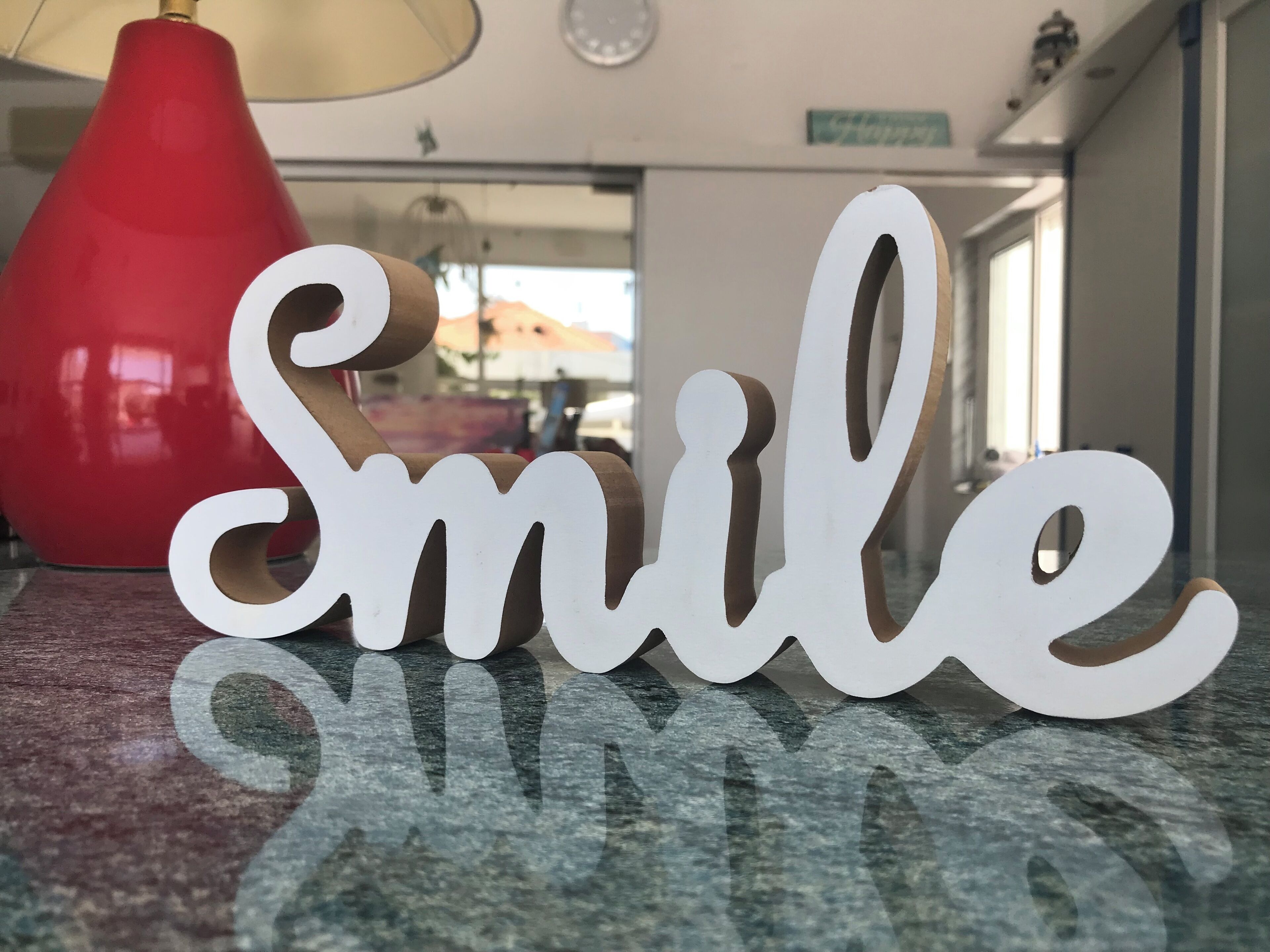 A decorative sign with the word "Smile" in a playful font, placed on a countertop.