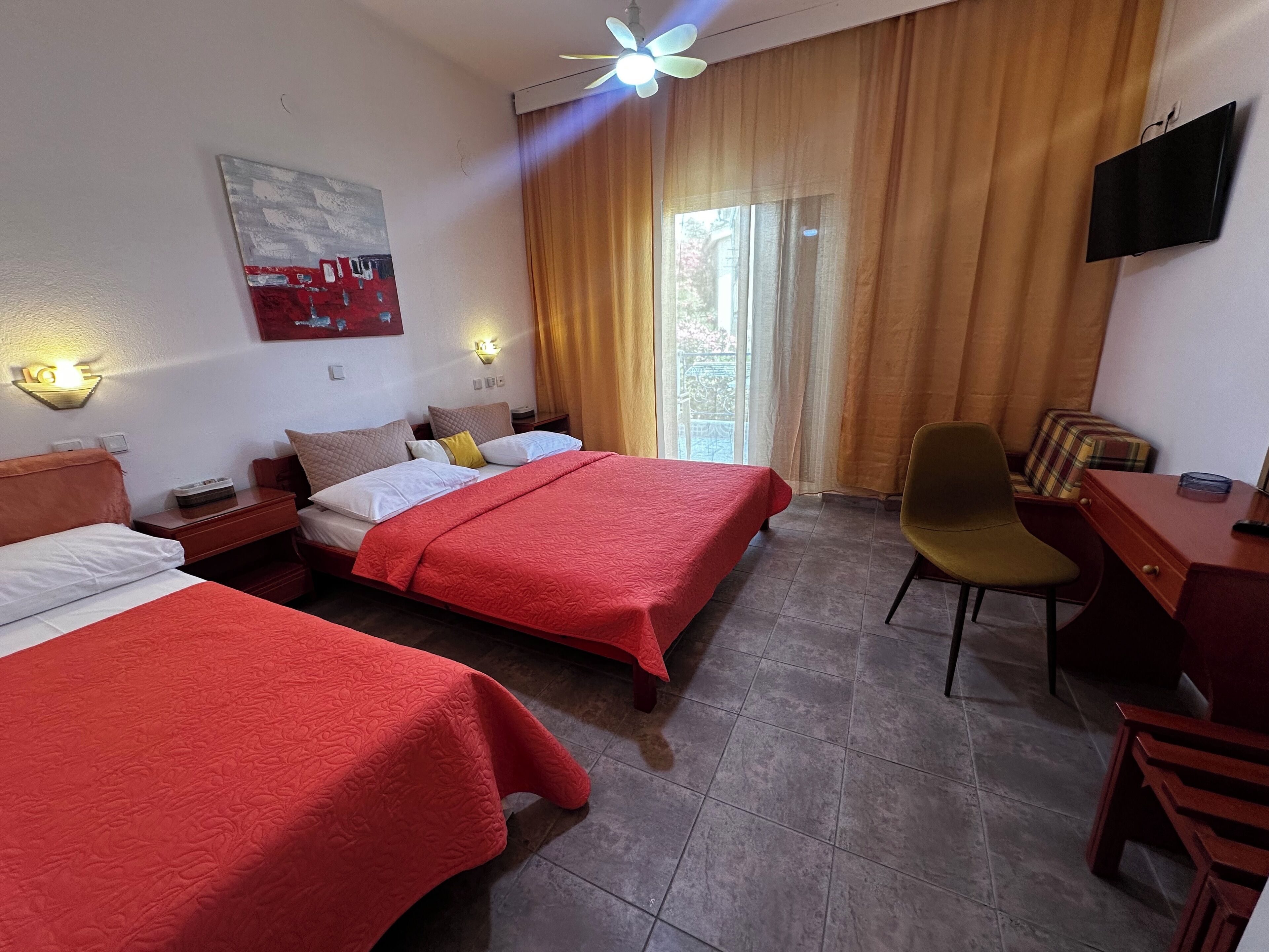 A hotel room with two beds, a desk, a chair, a TV, and a painting on the wall.