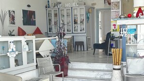 A hotel lobby with a reception desk, seating area, and a large decorative rug. - Victor-Eleni Hotel (Kassandra)