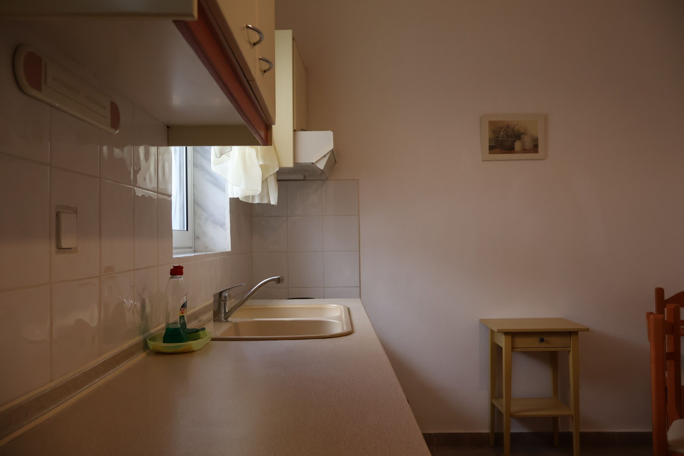A kitchen with a sink, a small table, and a cabinet.