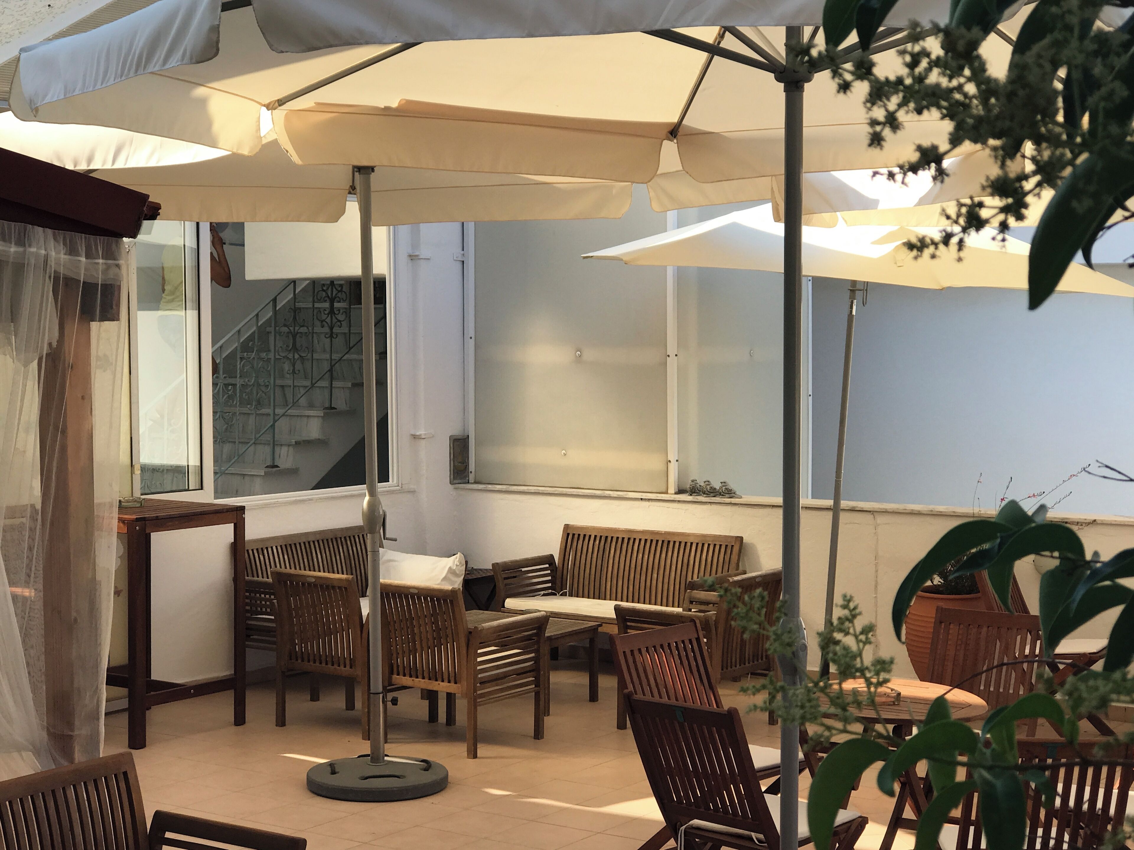 An outdoor seating area with wooden furniture and large umbrellas providing shade.