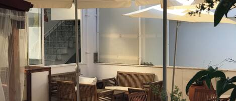 An outdoor seating area with wooden furniture and large umbrellas providing shade.