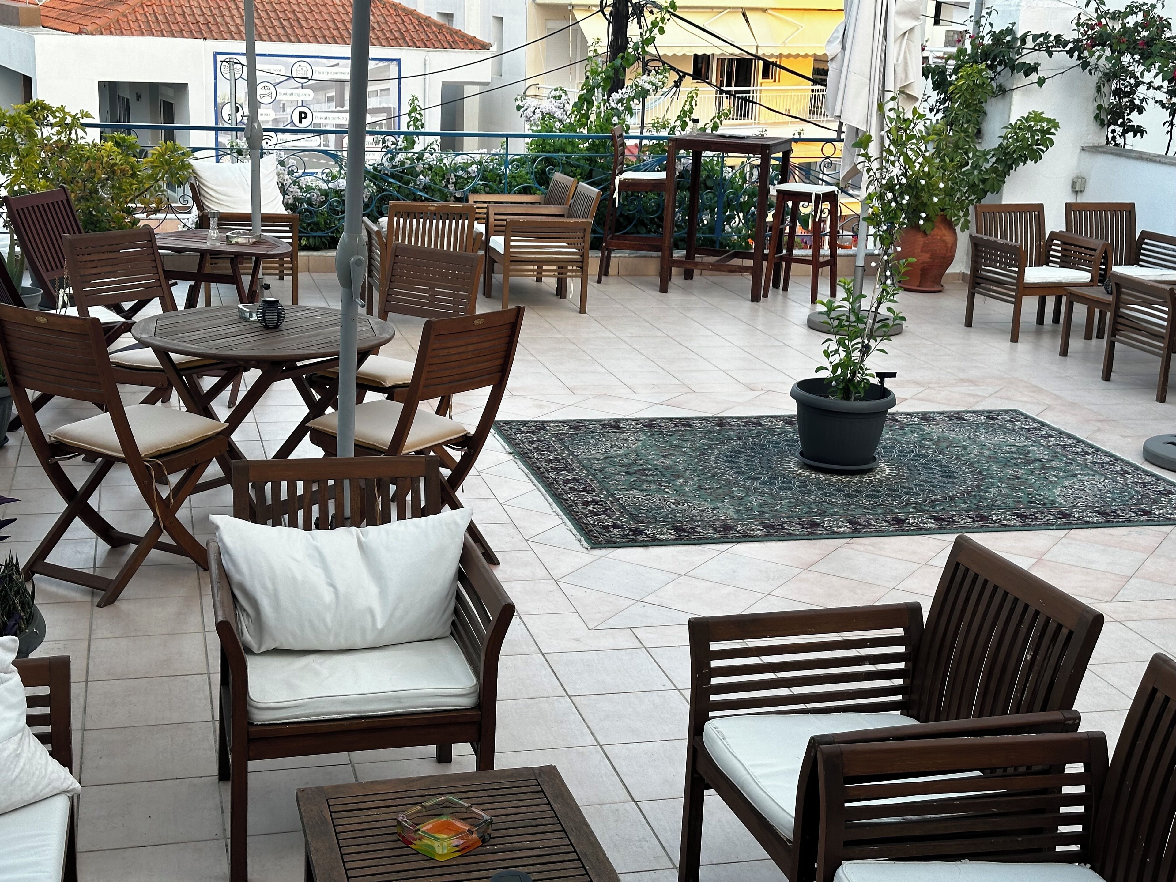 An outdoor patio area with wooden furniture, including tables and chairs, and a potted plant.