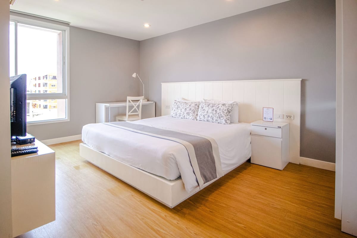 Une chambre moderne avec un grand lit, des tables de chevet, un bureau et un téléviseur.