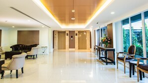 A spacious lobby with a polished floor, a grand piano, and a seating area with chairs and a table. - Cinnamon Hotel Bangkok (Bangkok)