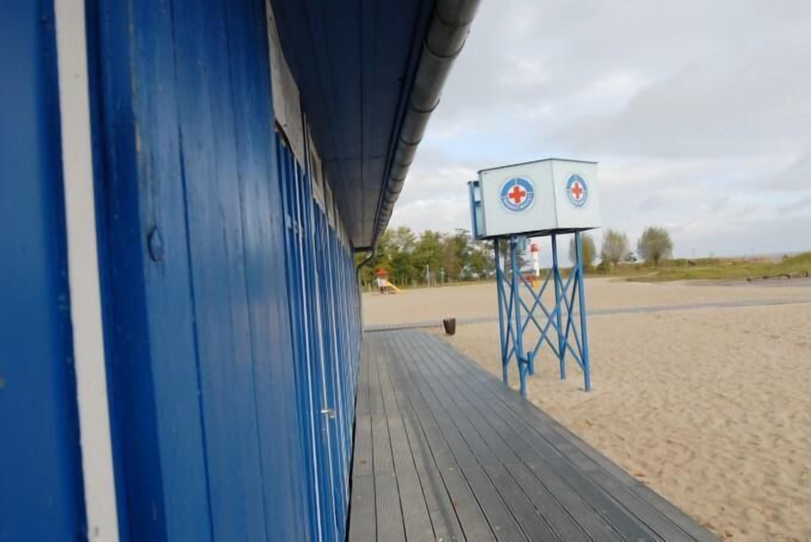 A beachside building with a blue exterior and a lifeguard tower with a red cross symbol.