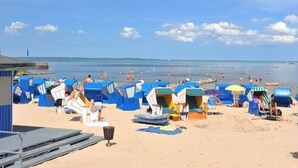 Une plage avec des cabanes de plage bleues et une zone sablonneuse.