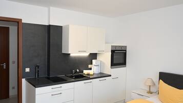 A modern kitchen with white cabinets, a black countertop, and a built-in oven.