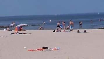 Uma praia com pessoas se bronzeando e nadando.