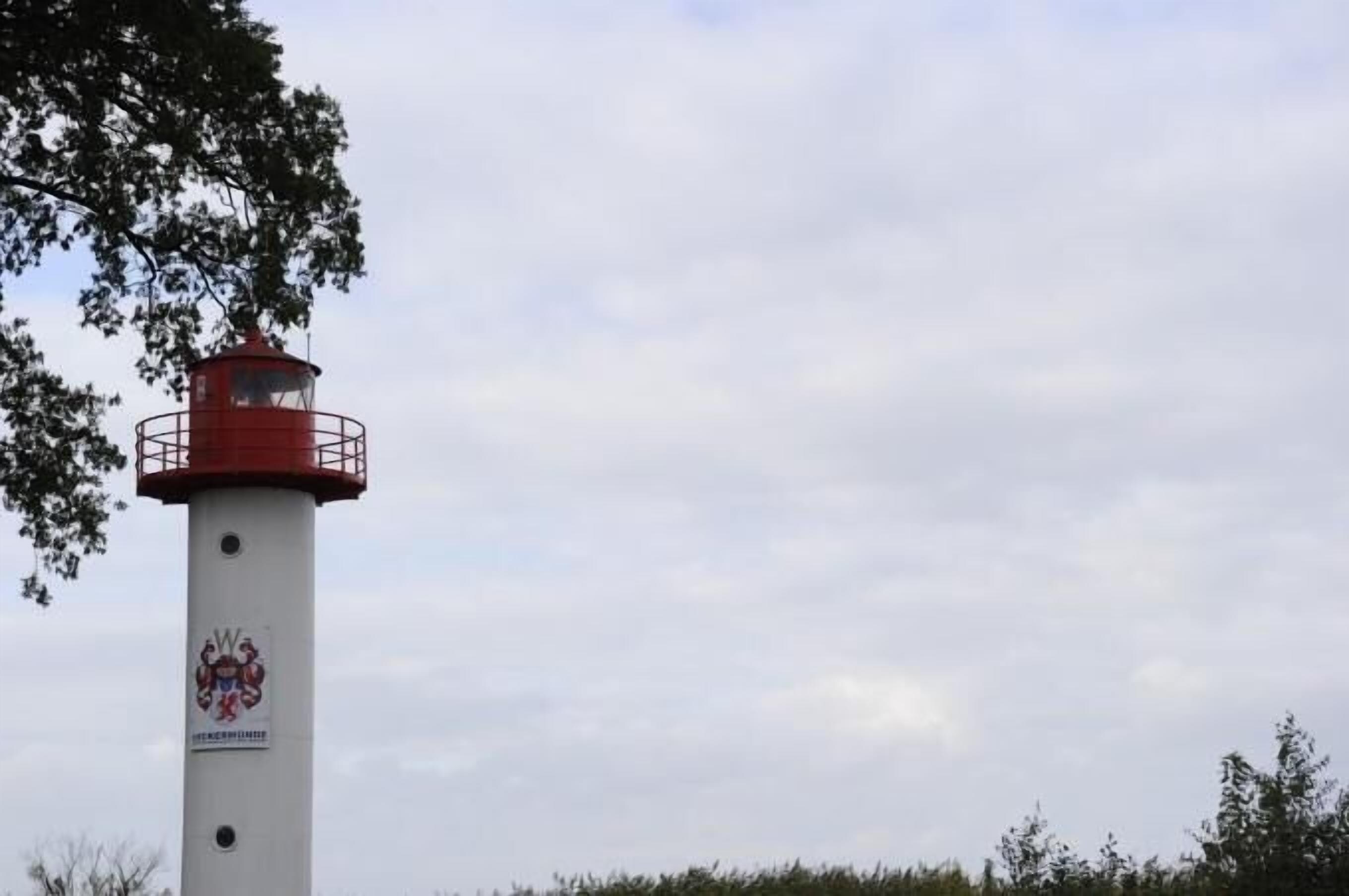 Een vuurtoren met een rode bovenkant en een witte basis, met een afbeelding van een familiewapen.