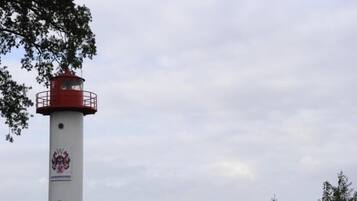 Een vuurtoren met een rode bovenkant en een witte basis, met een afbeelding van een familiewapen.