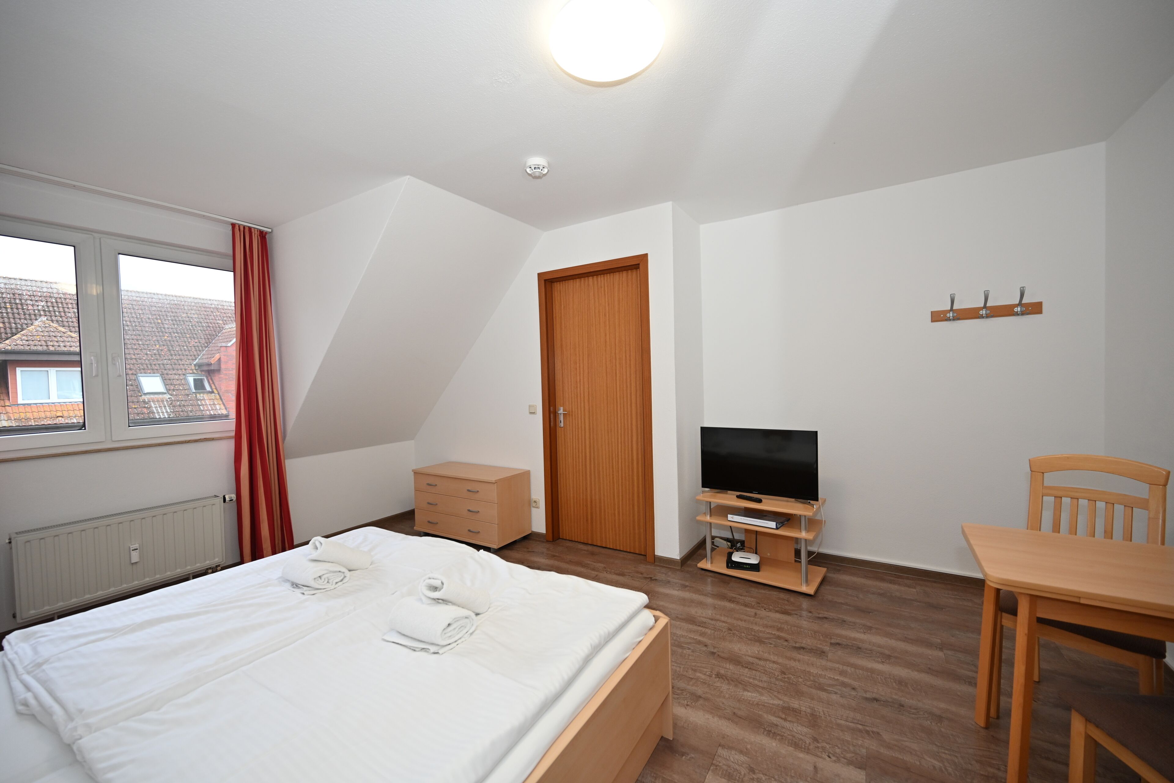 Ein Schlafzimmer mit einem Bett, einem Fernseher, einem Holztisch und einem Stuhl.