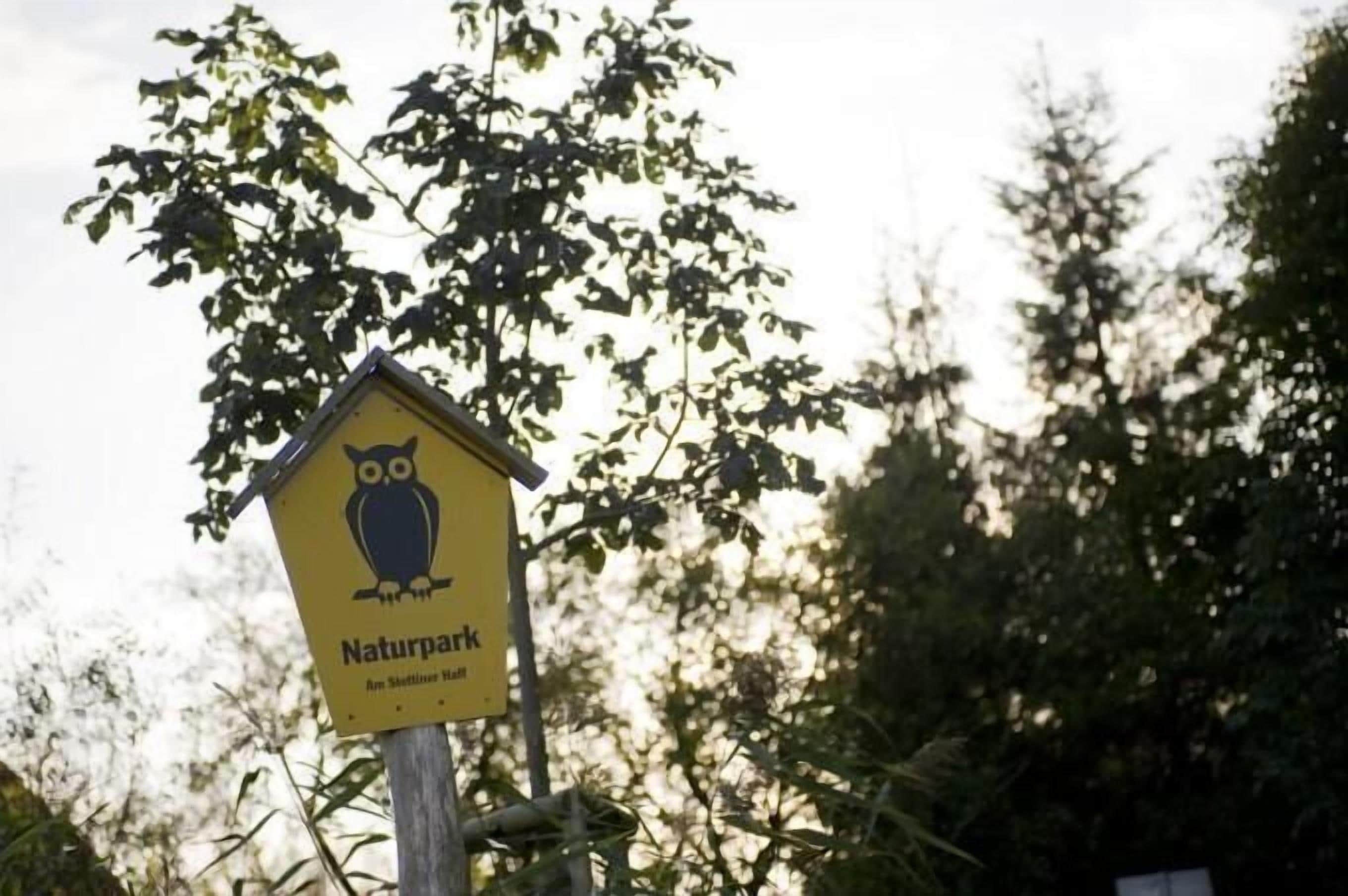Et gult skilt med en ugle og teksten "Naturpark", der markerer et naturområde.