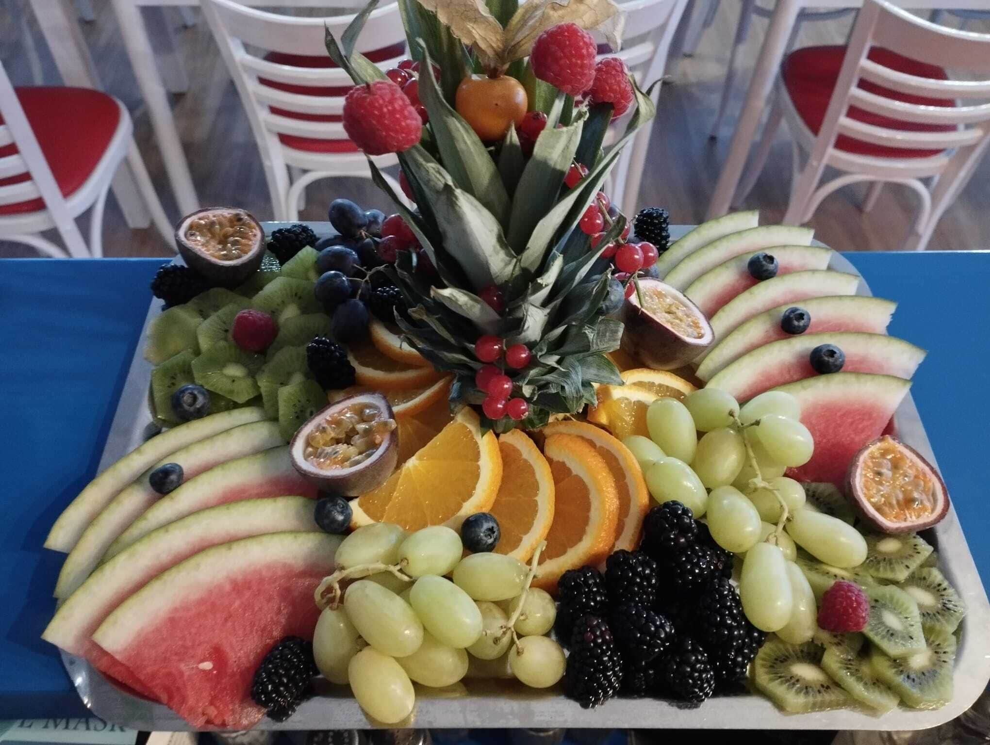 A fruit platter on a table with white chairs in the background.