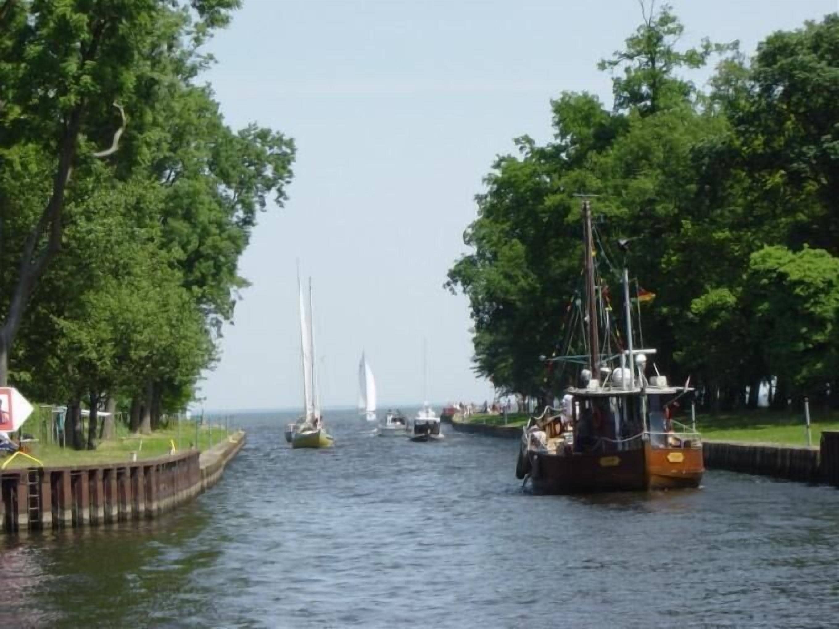 En kanal med både, omgivet af træer og en klar himmel.