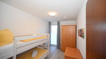 Ein Zimmer mit Stockbetten, einem Holzschrank und einer Tür mit einem farbenfrohen Kunstwerk.