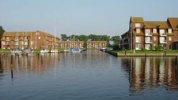 A canal with boats docked on the left and a row of apartment buildings on the right.