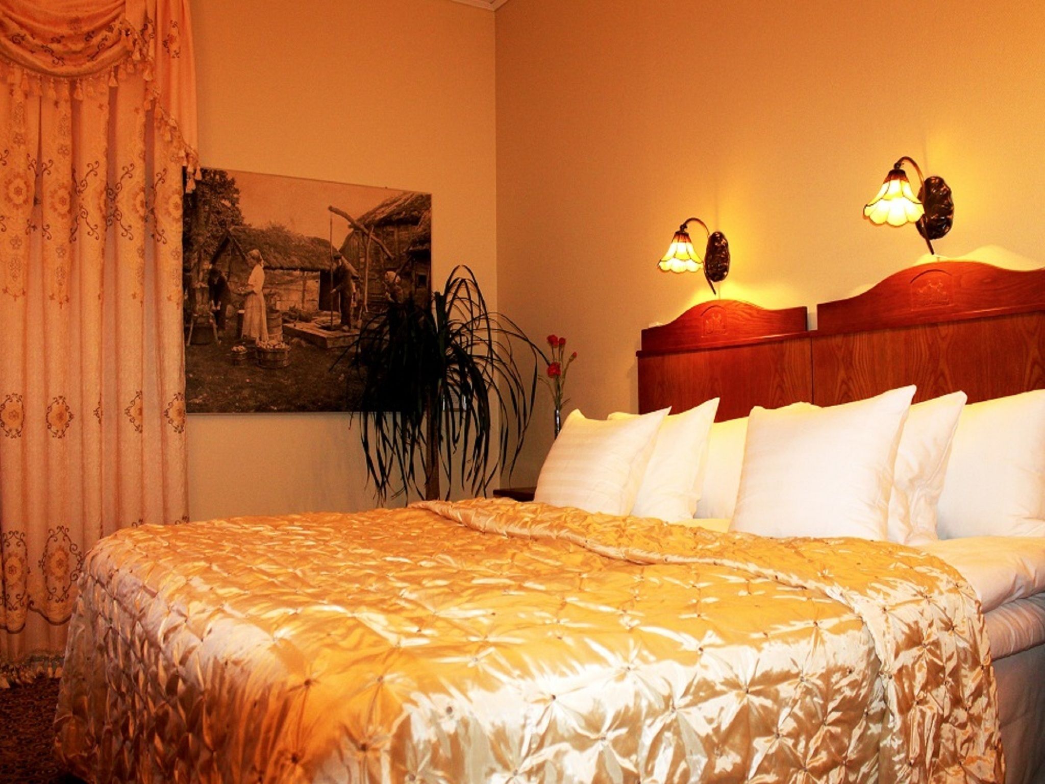 Una habitación de hotel con una cama grande, dos lámparas de noche, un cabecero y un cuadro en la pared.