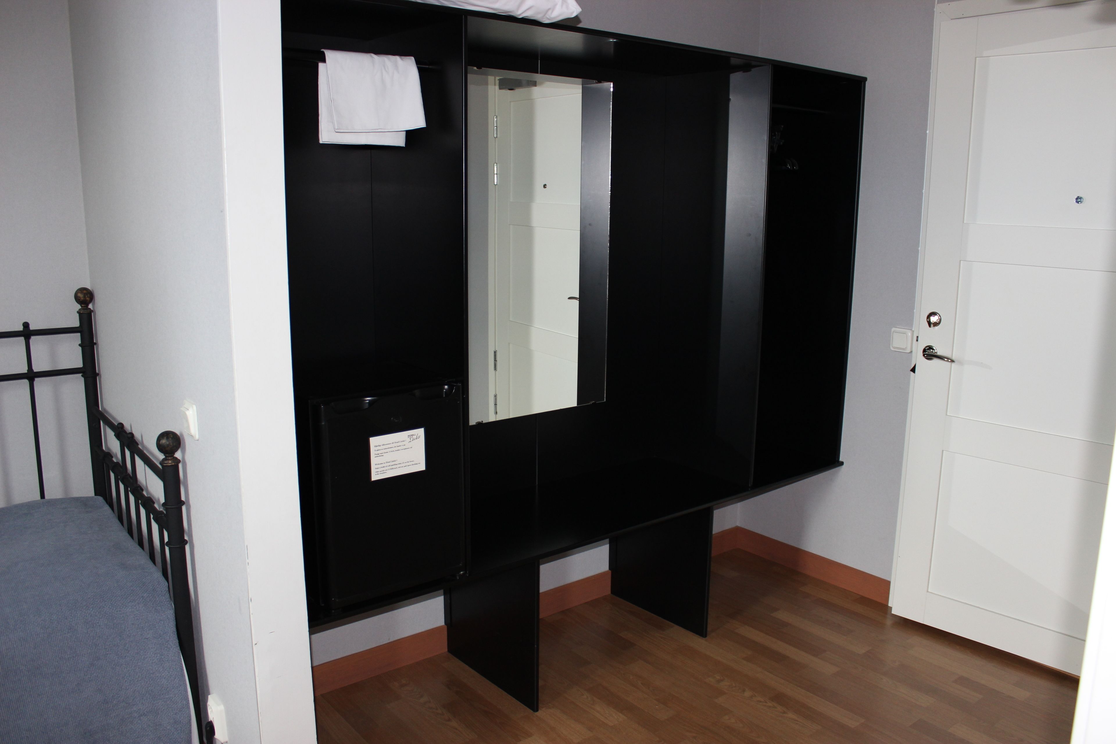 A bedroom with a bed, a large mirror, a wardrobe, and a door.