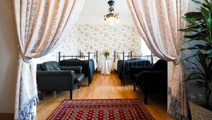 A bedroom with two black metal beds, a red patterned rug, and a potted plant. - Hotel Läckö (Lidköping)