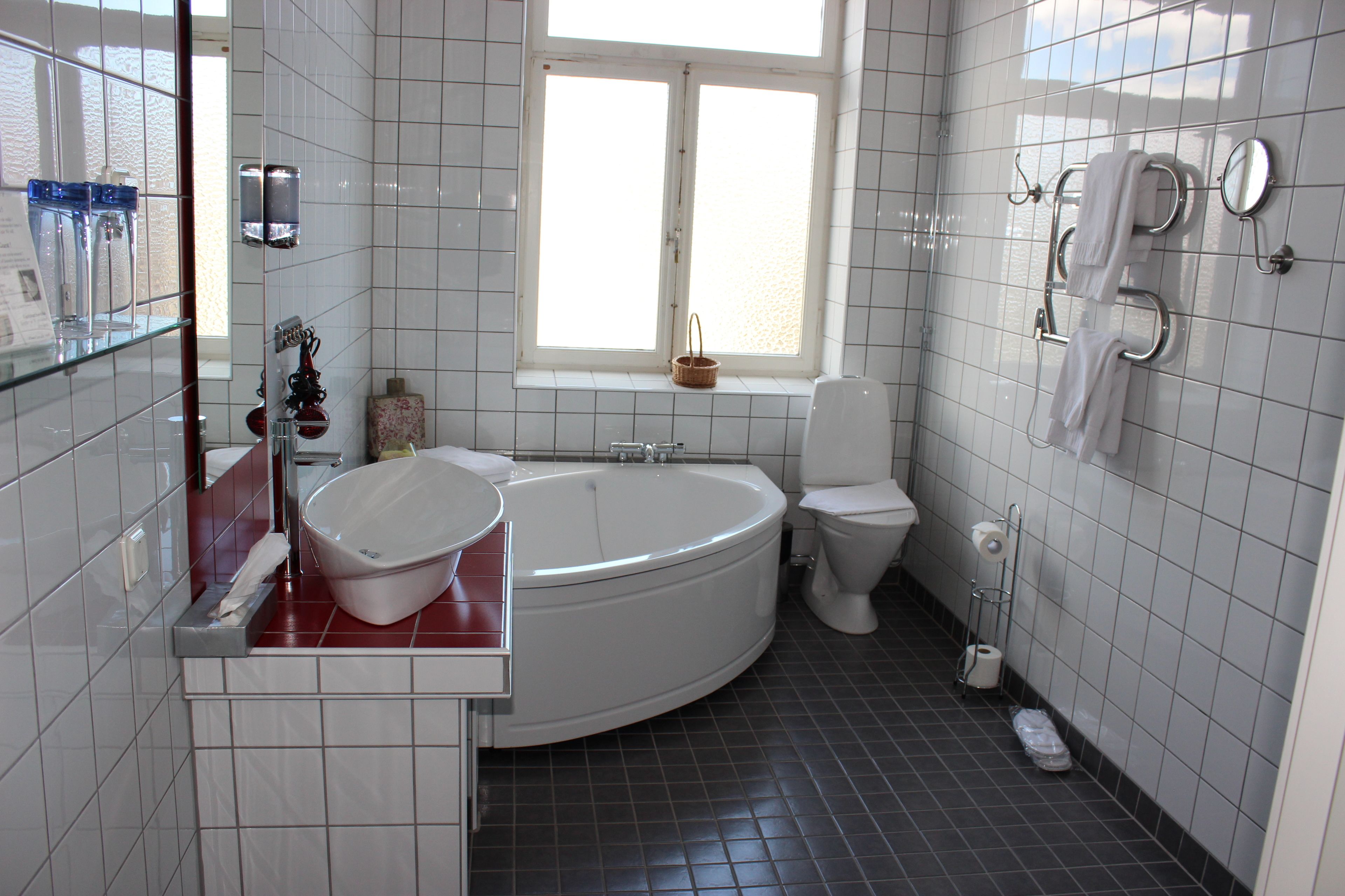 A modern bathroom with a freestanding bathtub, a toilet, and a window providing natural light.