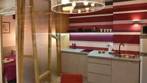 Une cuisine moderne avec un mur à rayures, une porte coulissante à cadre en bois et une chaise rouge.