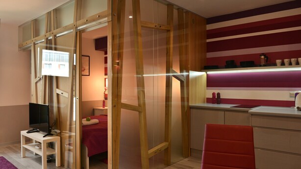 Une chambre avec un lit, une télévision, un bureau et une chaise rouge.