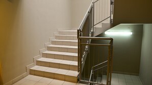 Un escalier avec une rampe métallique et un luminaire au bas.