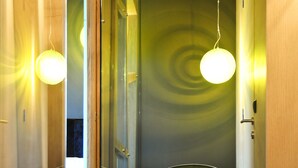 Une salle de bain moderne avec une douche à parois de verre, une baignoire ronde noire et une porte en bois.
