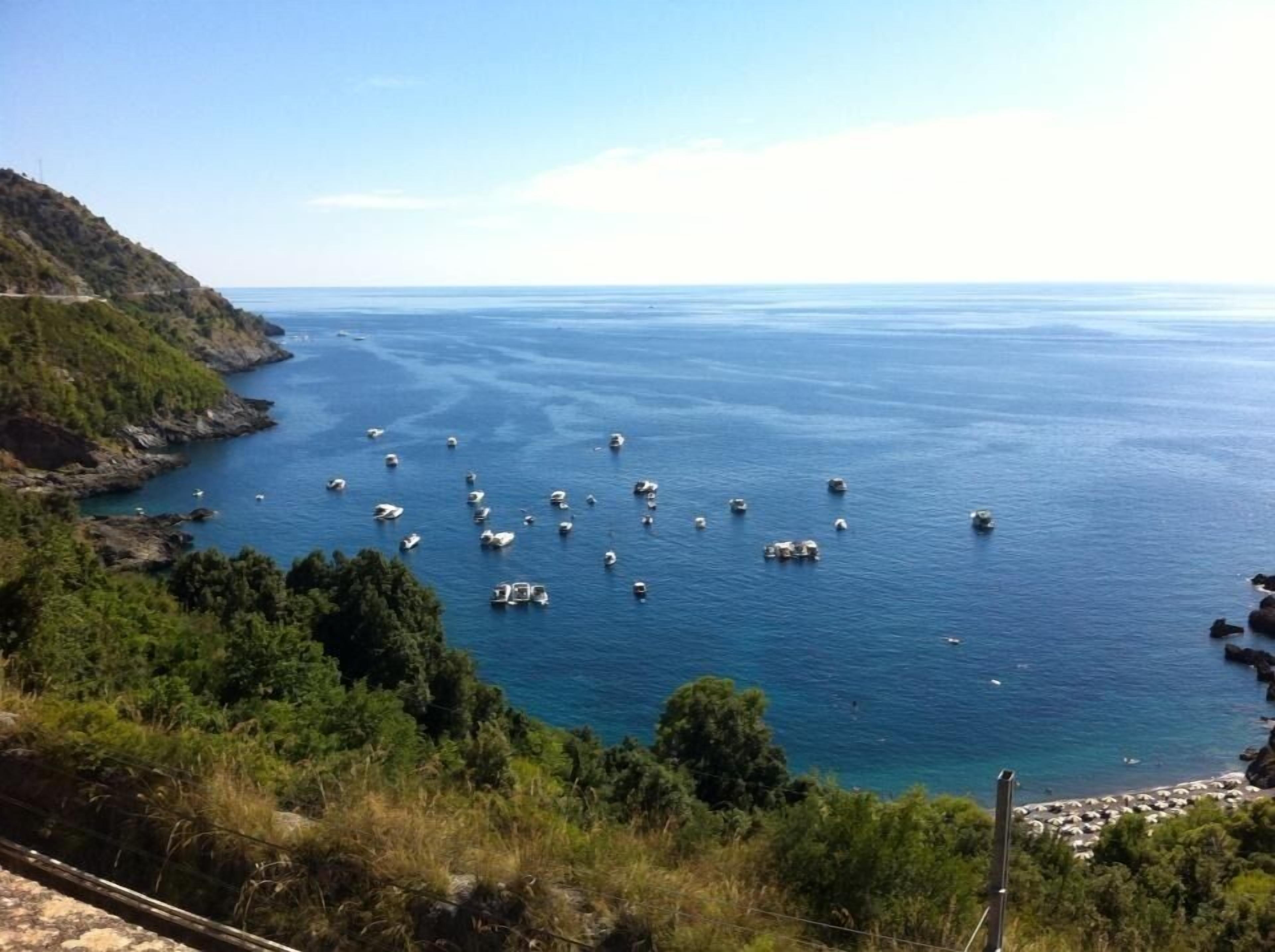 Un paisaje costero con barcos en el agua y una carretera a la izquierda.