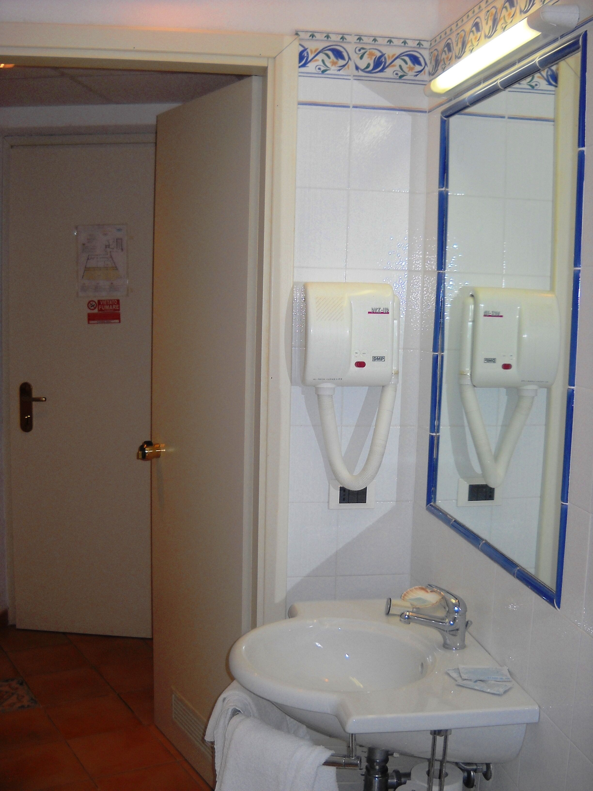 Un baño con lavabo, espejo y secador de manos.