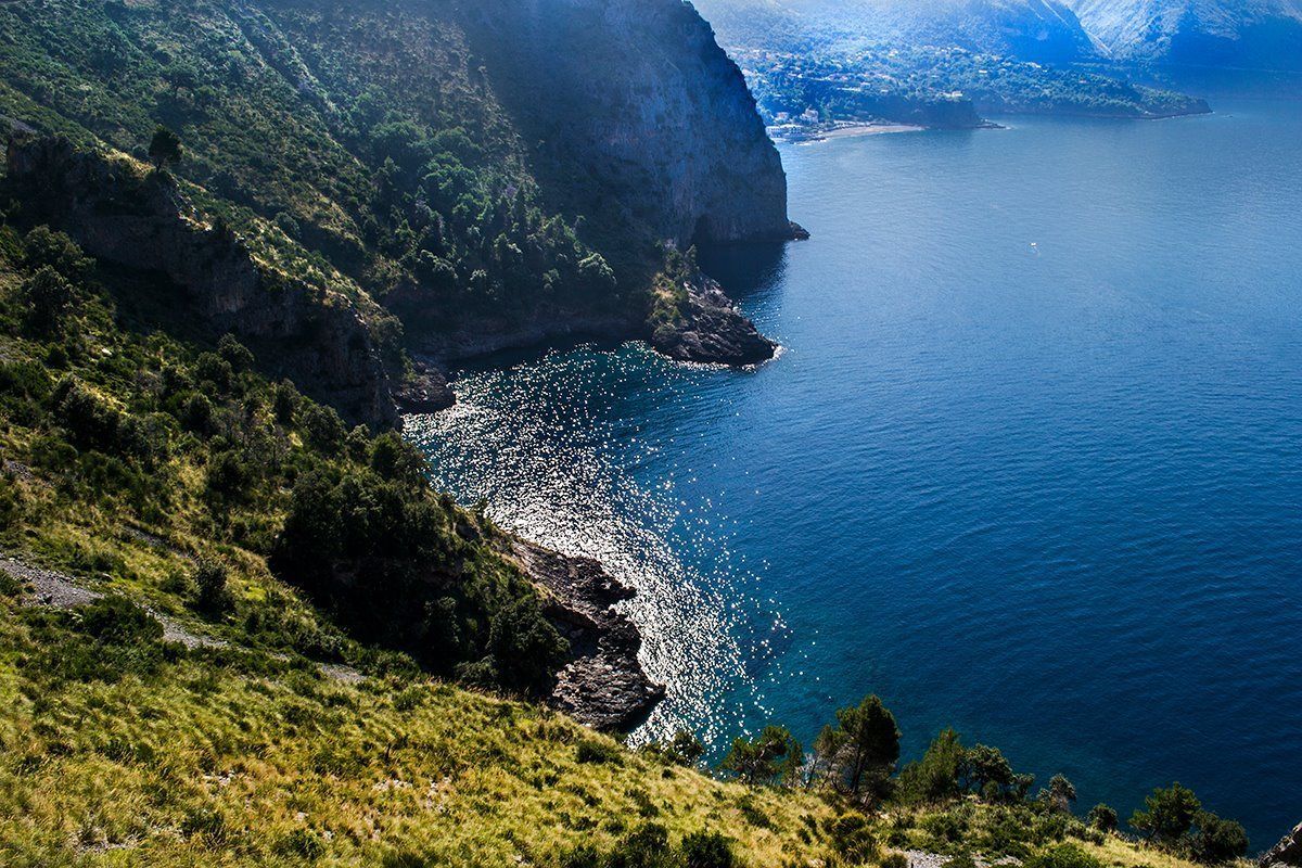 A coastal landscape with a steep cliff and a calm sea.