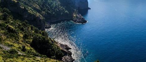 A coastal landscape with a steep cliff and a calm sea.