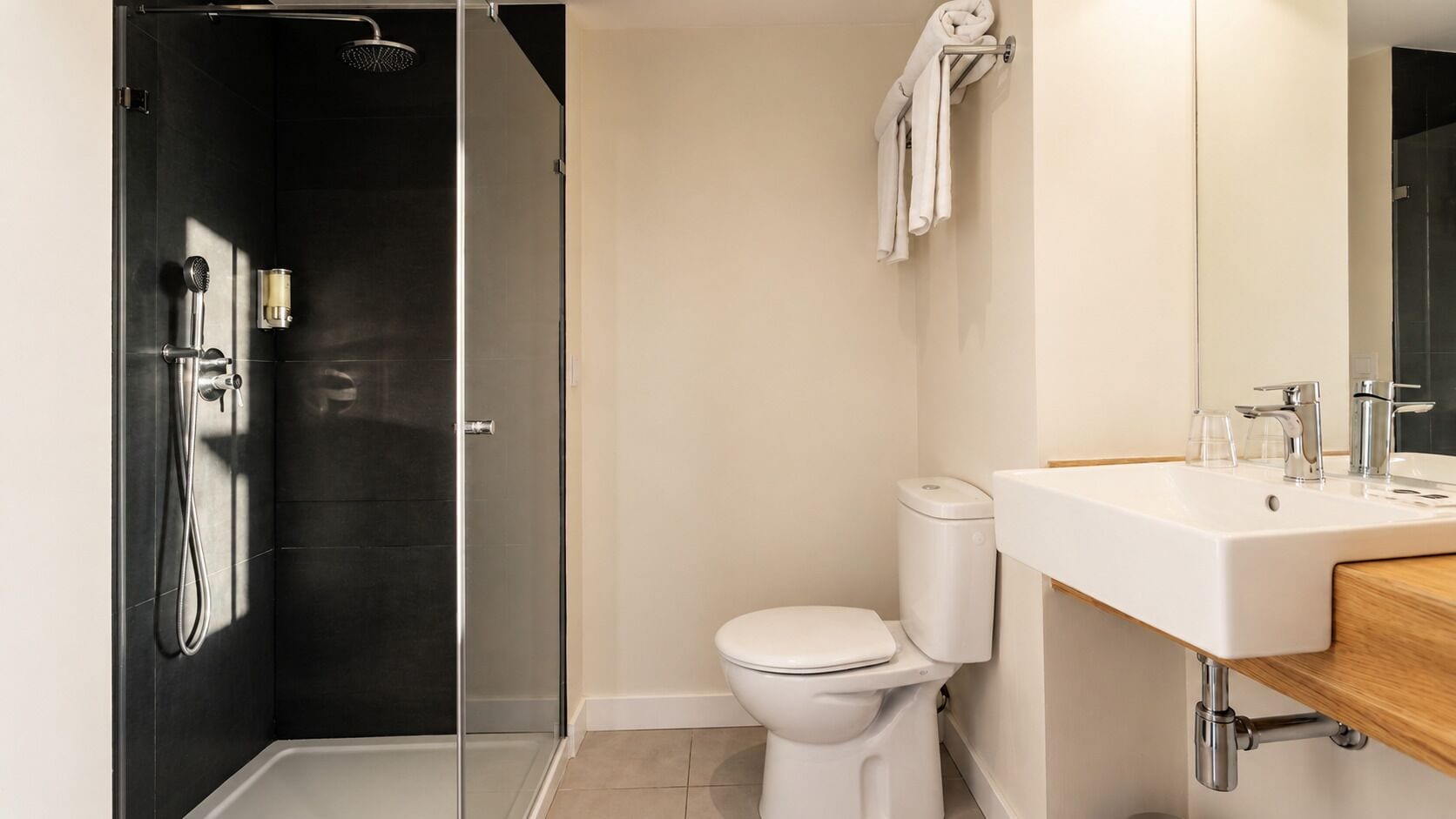 A modern bathroom with a glass-enclosed shower, a white toilet, and a wooden vanity with a sink.