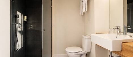 A modern bathroom with a glass-enclosed shower, a white toilet, and a wooden vanity with a sink.