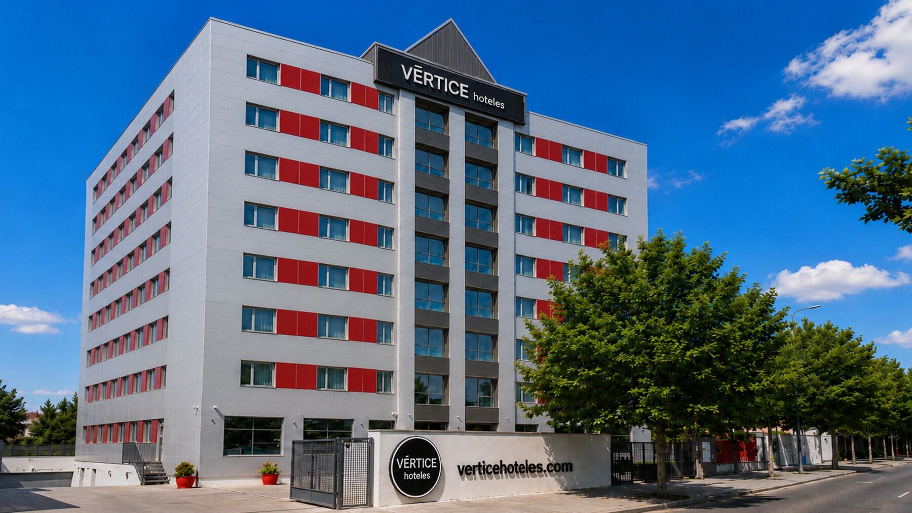 Un edificio de hotel de varios pisos con diseño moderno, que presenta un cartel llamativo en la parte superior.